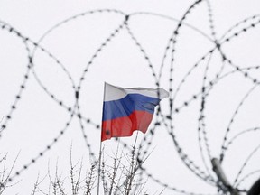 The Russian flag is seen through barbed wire as it flies on the roof of the Russian embassy in Kiev, Ukraine, March 2018.