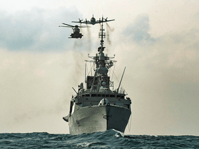 A CH-148 Cyclone helicopter and a CP-140 Aurora maritime patrol aircraft fly over the Royal Canadian Navy frigate HMCS Winnipeg in the Asia-Pacific Region during Operation NEON, November 15, 2020.