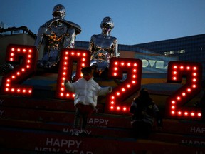 Ein Kind, das nach dem Ausbruch der Coronavirus-Krankheit (COVID-19) eine Gesichtsmaske trägt, geht am Silvesterabend in einem Einkaufszentrum in Peking, China, am 31. Dezember 2021 vor einer Installation von 2022.