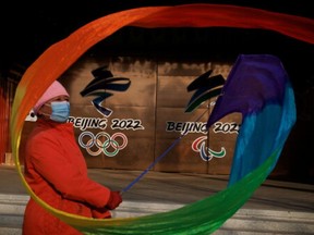 A woman flies a ribbon near the logos of the Beijing 2022 Olympic and Paralympic Games in a park in Beijing, China, December 8, 2021.