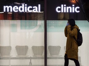 A pedestrian wearing a mask walks past a a Medical Clinic in Toronto during the COVID 19 pandemic.