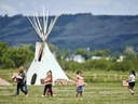 Gemeindemitglieder platzieren Solarleuchten neben Fahnen, die die Stellen markieren, an denen Überreste durch Bodenradar auf dem Gelände der ehemaligen Marieval Indian Residential School auf der Cowesses First Nation in Saskatchewan, 26. Juni 2021, entdeckt wurden.