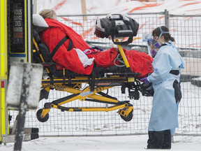 Paramedics transfer a patient from an ambulance into a hospital in Montreal in this Jan. 9, 2022 photo. Quebec is now seeking to charge residents extra for health-care as punishment for not getting the COVID-19 vaccine.