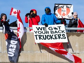 Supporters of truckers protesting the Liberal government’s vaccine mandate and other measures gather on an overpass on Ontario's Highway 416 as the convoy makes its way to Ottawa on Jan. 28, 2022.