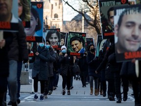 Auf diesem Foto, das am 8. Januar 2021 aufgenommen wurde, halten Menschen Schilder mit Bildern der Opfer des abgeschossenen Fluges PS752 der Ukraine International Airlines, der von der iranischen Revolutionsgarde in der Nähe von Teheran abgeschossen wurde, als sich Familie und Freunde versammeln, um an einem Marsch zum zum ersten Jahrestag in Toronto, Ontario, Kanada