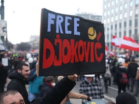 A man holds a placard reading "Free Djokovic" as people demonstrate against the Austrian government's measures taken in order to limit the spread of the coronavirus during a protest on January 8, 2022 in Vienna, amid the novel coronavirus / COVID-19 pandemic