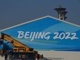 In this file photograph taken on January 4, 2022, workers set up a banner on the sign of a building at the Beijing Olympic Park in Beijing, host to the 2022 Winter Olympic Games.