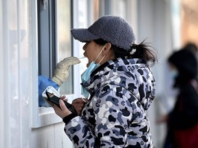 A woman receives a throat swab to test for COVID-19 in Beijing. China's capital city has been put on high alert as it prepares to host the Beijing 2022 Winter Olympics and Paralympics which open next month