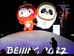 People are seen in front of an installation displaying Bing Dwen Dwen, right, and Shuey Rhon Rhon, respective mascots of the 2022 Beijing Winter Olympic and Paralympic Games, along a street in Beijing.