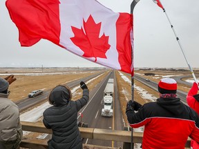 Supporters of the Freedom Convoy that is protesting the federal vaccine mandate for truckers gather on an overpass over the Trans-Canada Highway east of Calgary on Jan. 24, 2022.