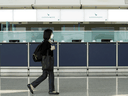 Eine Frau geht nach neuen Maßnahmen zur Kontrolle von COVID-19-Infektionen in Hongkong am 11. Januar 2022 an leeren Schaltern von Cathay Pacific am internationalen Flughafen Hongkong vorbei.
