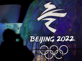 A man photographs an illuminated logo ahead of the 2022 Winter Olympics in Beijing, China, on Jan. 26, 2022.