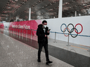 Een man loopt langs een reclamebord dat reclame maakt voor de Olympische Winterspelen van 2022 op Beijing Capital International Airport.  Mensen die de wedstrijden bijwonen, moeten binnen 96 uur na vertrek naar China twee tests voor COVID-19 afleggen, en een van de tests wordt binnen 72 uur na vertrek gedaan.