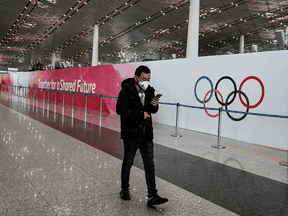 A man walks past a billboard promoting the 2022 Winter Olympic Games, at Beijing Capital International Airport. People attending the Games must take two COVID-19 tests within 96 hours of their departure to China, one of the tests being within 72 hours of departure.
