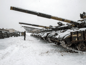 Ein ukrainischer Soldat steht am 31. Januar 2022 vor Panzern, die in seiner Basis in der Nähe von Klugino-Bashkirivka in der Region Charkiw in der Ukraine geparkt sind.