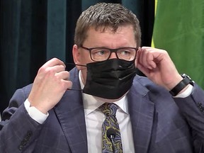 Saskatchewan Premier Scott Moe adjust his face mask at a news conference Wednesday during which he intermittently removed it to speak to the news media.