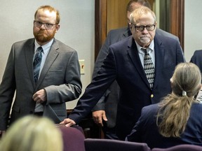 Greg McMichael and his son, Travis McMichael, left, enter for the reading of the jury's verdict in the Glynn County Courthouse on November 24, 2021 in Brunswick, Georgia.