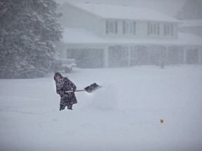 Heavy snow makes shoveling particularly difficult for Andra Morrison in a neighborhood of Nepean near Ottawa.