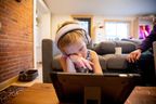Willa Stief does online schooling while her parents work from home and take care of Willa, her twin sister and a toddler, in Hamilton, Ont., on Jan. 7, 2022, while schools remain closed in the province. They are currently scheduled to reopen on Jan. 17.
