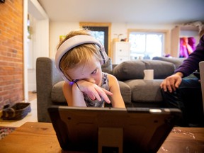 Willa Stief does online schooling while her parents work from home and take care of Willa, her twin sister and a toddler, in Hamilton, Ont., on Jan. 7, 2022, while schools remain closed in the province. They are currently scheduled to reopen on Jan. 17.