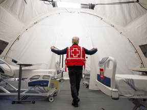 A Red Cross volunteer walks between beds in a mobile hospital set up to help care for COVID-19 patients in Montreal, April 26, 2020. Hospitals in Quebec and Ontario are currently being pushed to the breaking point by the effects of the Omicron variant.