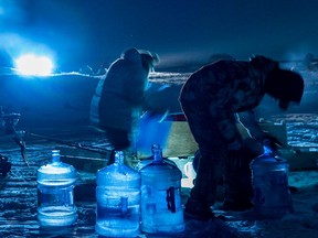 Einwohner von Iqaluit sammeln Flusswasser durch in das Eis gehauene Löcher in der Nähe von Iqaluit, Nunavut, am Freitag, den 14. Januar 2022.