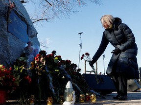 A woman places flowers during a ceremony marking the second anniversary of the Ukraine International Airlines flight PS752 downing in Iranian airspace, in Kyiv, Ukraine on Jan. 8, 2022.