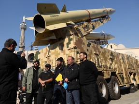 Iranians take photos during an exhibition displaying missiles of the kind used during Iran’s retaliatory strike on the U.S Ayn al-Asad military base in 2020 are seen on display at Imam Khomeini Grand Mosalla in Tehran Jan. 7, 2022.