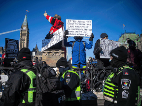 Police keep an eye on protesters gathered around Parliament Hill and Ottawa's downtown core for the Freedom Convoy protest on Sunday January 30, 2022.