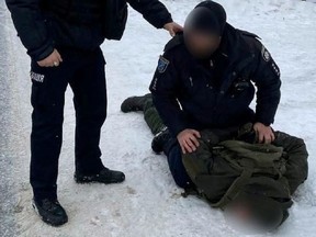 Ukrainian police officers detain a soldier, named by the Interior Ministry as Artem Ryabchuk, on suspicion of murdering people at a military factory in the Dnipropetrovsk region, Ukraine, on Jan. 27.