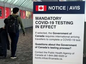 A traveller walks past a "Mandatory COVID-19 Testing" sign at Pearson International Airport during the coronavirus disease (COVID-19) pandemic in Toronto, Ontario, Canada, December 18, 2021.  REUTERS/Carlo Allegri