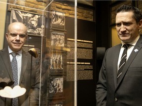 Quebec Environment and Anti-Racism Minister Benoit Charette, right, listens as he told the story of a small gift given to Fania Fainer for her 20th birthday while a prisoner at the Auschwitz concentration camp. Museum director Daniel Amar, left, looks on, in Montreal, on Friday, Feb. 4, 2022.