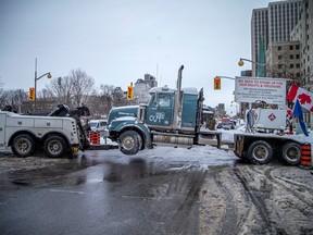 A Freedom Convoy rig is towed away Sunday as city workers restore the area around Parliament Hill back to normal.