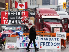 A protester walks in front of parked trucks as demonstrators continue to protest COVID-19 restrictions, in Ottawa on Feb. 8.