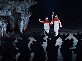 Torch bearers Dinigeer Yilamujiang and Jiawen Zhao of Team China hold the Olympic flame during the Opening Ceremony of the Beijing 2022 Winter Olympics at the Beijing National Stadium on February 04, 2022 in Beijing, China.