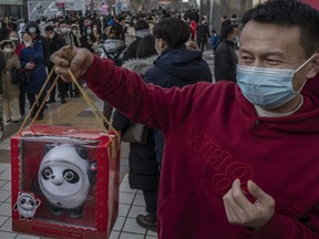 A man holds his purchase of the mascot Bing Dwen Dwen for a photo as hundreds line up to enter the official Beijing 2022 Winter Olympics flagship store on Feb. 6. Crowds of people have been gathering outside the official stores in the Chinese capital after online sites sold out of the most popular items, including mascots Bing Dwen Dwen and Shuey Rhon Rhon, according to reports.