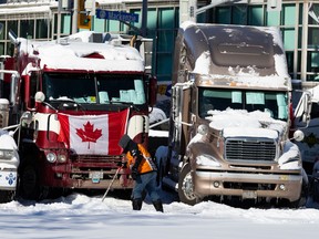 A man shovels near trucks that remain on Rideau Street, as part of the ongoing occupation of Ottawa, on Feb. 18.
