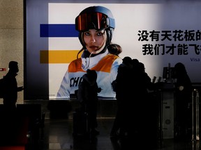 People line up to board a train near an image of freestyle skier Eileen Gu at a railway station ahead of the Beijing 2022 Winter Olympics, during the Chinese Lunar New Year holiday, in Beijing, China February 3, 2022.