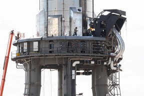 A man walks across the platform holding SpaceX’s first orbital Starship SN20 stacked atop its massive Super Heavy Booster 4 at the company’s Starbase facility near Boca Chica Village in South Texas on Feb. 10, 2022.