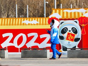 A Beijing 2022 Winter Olympics staff member walks past an Olympic logo in Beijing on Sunday, January 30, 2022.