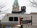 In this Feb 6 photo, a man sits on top of a camper in front of Parliament Hill during the ongoing trucker blockade of downtown Ottawa.  