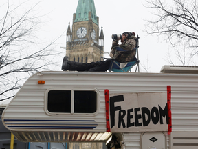 In this Feb 6 photo, a man sits on top of a camper in front of Parliament Hill during the ongoing trucker blockade of downtown Ottawa.