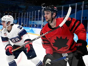 Canada's Maxim Noreau (R) and USA's Sean Farrell chase the puck during the men's preliminary round group A match of the Beijing 2022 Winter Olympic Games ice hockey competition.