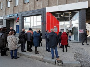 People stand in a line to use an ATM money machine in the separatist-controlled city of Donetsk, Ukraine February 21, 2022. REUTERS/Alexander Ermochenko