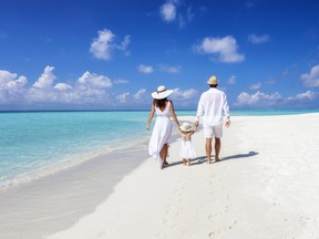 A beautiful family walks together on a tropical paradise beach in the Maldives