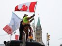 People wave flags on top of a truck in front of Parliament Hill in Ottawa, on Feb. 6, 2022, during the Freedom Convoy truckers' protest against vaccine mandates and other COVID measures.