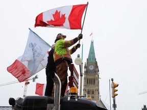 People wave flags on top of a truck in front of Parliament Hill in Ottawa, on Feb. 6.