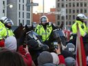 Demonstranten stehen vor kanadischen Polizeibeamten auf Pferden, während Trucker und Unterstützer am 18. Februar 2022 in Ottawa, Ontario, Kanada, weiterhin gegen die Impfmandate gegen die Coronavirus-Krankheit (COVID-19) protestieren.