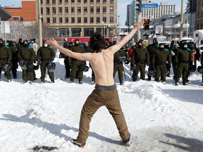 A topless man gestures in front of police officers, as truckers and supporters continue to protest coronavirus disease (COVID-19) vaccine mandates, in Ottawa, Ontario, Canada, February 18, 2022. REUTERS/Lars Hagberg
