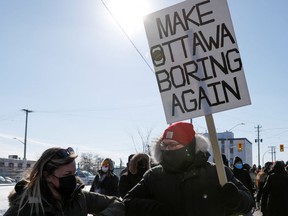 Eine Person hält ein Schild, während Menschen an einem Gegenprotest teilnehmen, der einen kleinen Konvoi von Truckern blockiert, die am 13. Februar 2022 in den Außenbezirken von Ottawa in Ontario, Kanada, gegen die Impfmandate gegen die Coronavirus-Krankheit (COVID-19) protestieren
